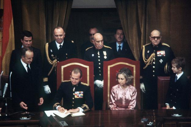 El rey Juan Carlos sanciona la Constitución en diciembre de 1978, ante la mirada de doña Sofía y el entonces Príncipe de Asturias. :: efe