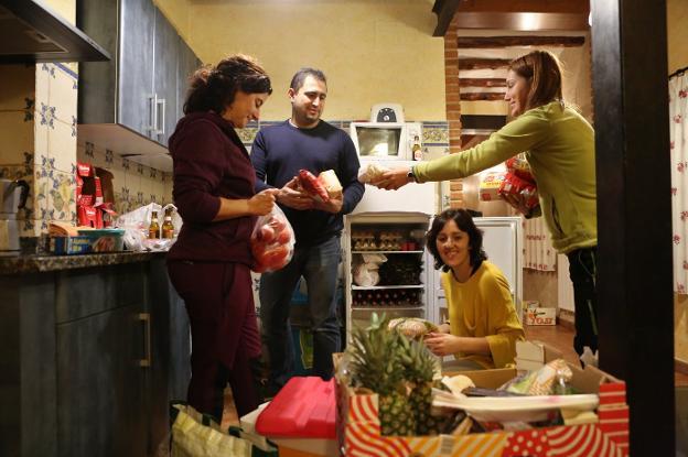 Los padres van organizando para que todo quepa en el frigorífico. 