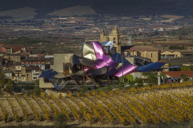 Imagen del hotel diseñado por Gehry, sobre los viñedos y con Elciego al fondo :: 