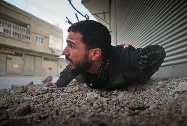 Un hombre intenta reguardarse durante un bombardeo contra rebeldes registrado en Arbin. :: A. A. / afp