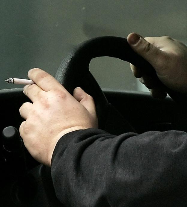 Un conductor sujeta un cigarrillo mientras conduce. :: L.r.M.