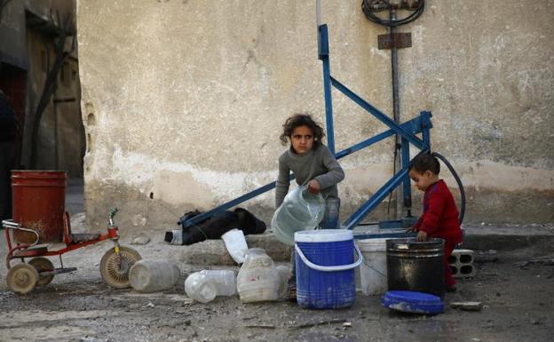 Niños recogen agua en Damasco.