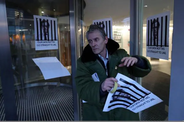 Un hombre pega carteles que piden la cárcel para el consejero delegado de Cambridge Analytica. :: / afp
