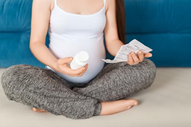 Una embarazada lee el prospecto de un medicamento antes de ingerir una dosis. :: r. c.