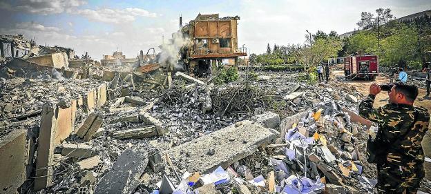 Precisión. Un soldado sirio fotografía uno de los centros derribados por los misiles aliados en el norte de Damasco. 