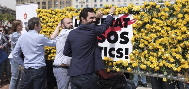 El presidente del Parlament, Roger Torrent, coloca flores amarillas en un mural colocado en la barcelonesa Plaza de Catalunya. :: marcel.li sáenz