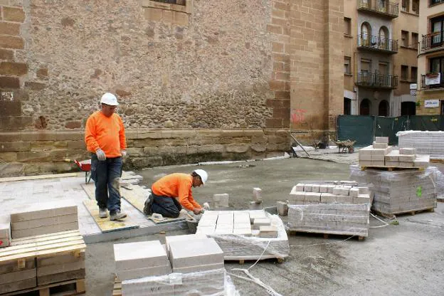 Dos de los operarios de Proviser colocan las losas descontaminantes sobre el suelo de la plaza. :: F. D.