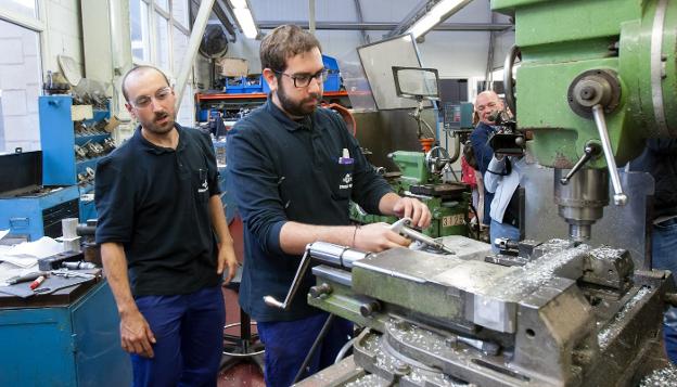 Mario Martínez, estudiante de FP Dual en prácticas manipula una máquina en la empresa Standard Profil, junto a un trabajador. :: díaz uriel
