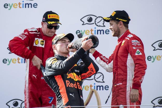 Max Verstappen, entre Kimi Räikkönen (i) y Sebastian Vettel, bebe en el podio para celebrar su victoria en el GP de Austria en Spielberg. :: EFE