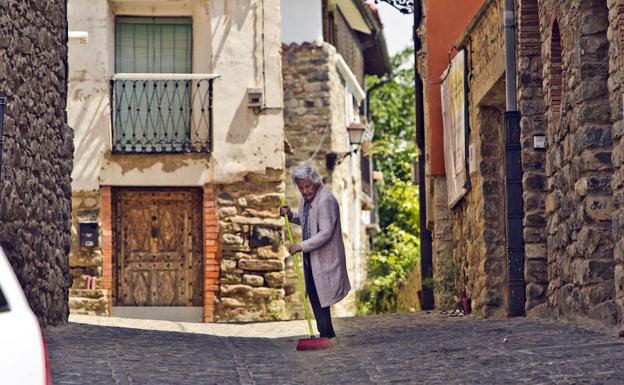 Una mujer barre a media mañana las calles de San Román de Cameros.