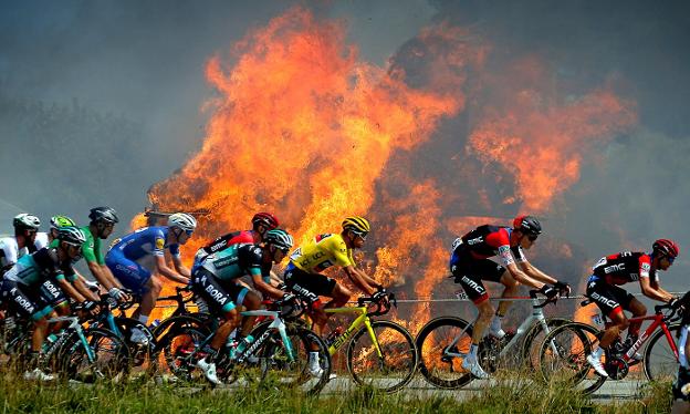 El pelotón se dirige hacia la meta en una imagen espectacular provocada por unas balas de heno en llamas. :: Stephane Mahe / AFP