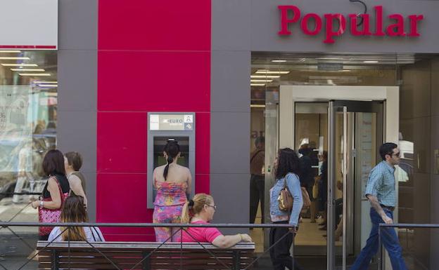 Clientes sacan dinero del cajero de una oficina del Banco Popular en Madrid. 