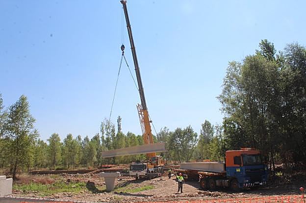 La grúa coloca la primera de las seis vigas de la pasarela.