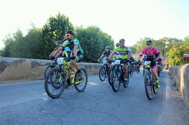  Salida. Cristina Sanz Cerrajería adelanta a otros ciclistas sobre el puente del Tirón en Tirgo.