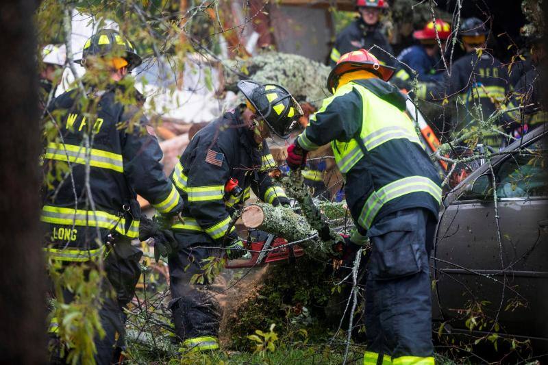 Trabajadores de los equipos de rescate retiran un árbol que ha caído en una vivienda matando a dos personas e hiriendo a una tercera.