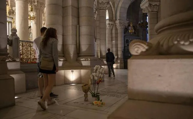Una pareja pasea por la cripta de la catedral de la Almudena, al lado de la tumba de los Franco, con algunas flores. 
