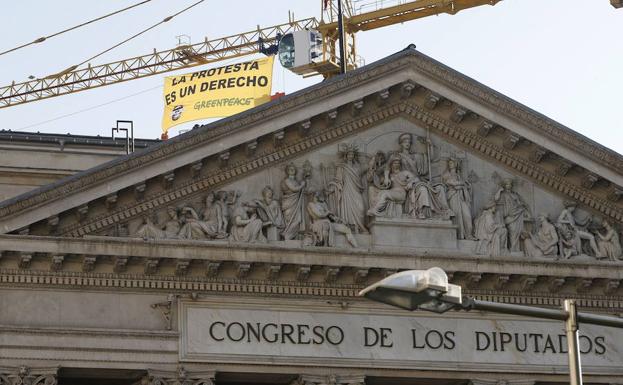 Imagen de junio de 2015 de tres activistas de Greenpeace desplegando una pancarta en una grúa situada junto al Congreso de los Diputados contra la 'ley mordaza'. 