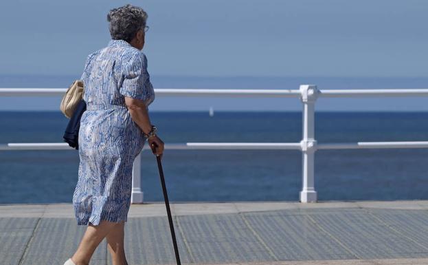 Una anciana camina por el paseo marítimo de una ciudad española. 