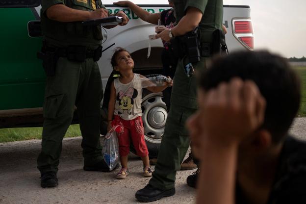Una niña hondureña asiste a una conversación entre miembros de la patrulla fronteriza en un paso de Texas. :: Adrees Latif / reuters
