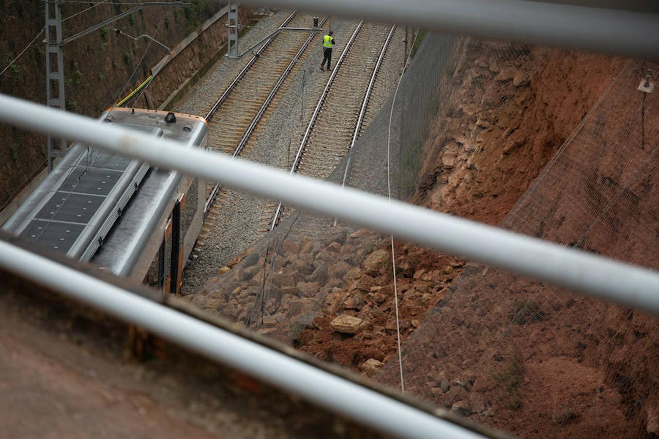 Detalle del derrumbamiento de piedras y tierra contra la red de contención instalada sobre la vía.