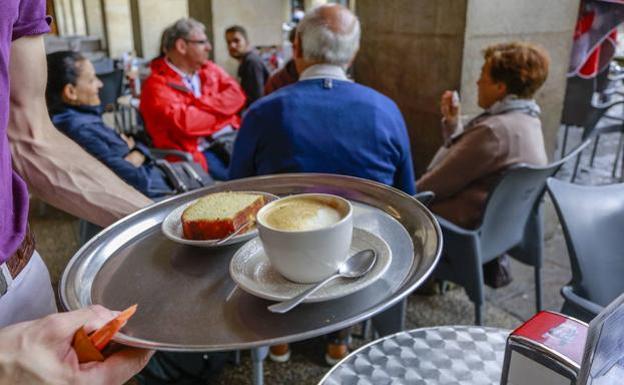 Un camarero lleva un servicio a varios clientes en un bar del centro de Vitoria.