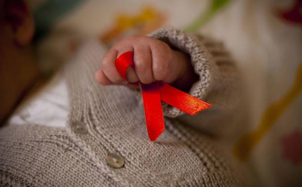 Un enfermo sostiene un símbolo de la lucha contra el sida. 