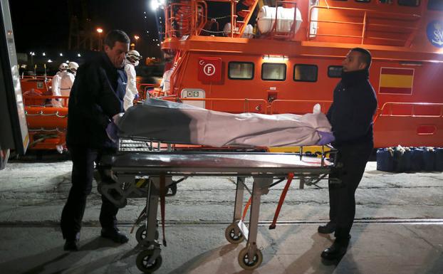 El cadáver de la inmigrante muerta en la patera interceptada en el mar de Alborán es trasladado a tierra, a su llegada al puerto de Málaga.