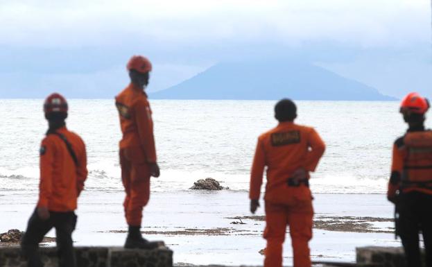 Miembros de los servicios de rescate observan el volcán Anak Krakatau desde la playa Carita en Indonesia.