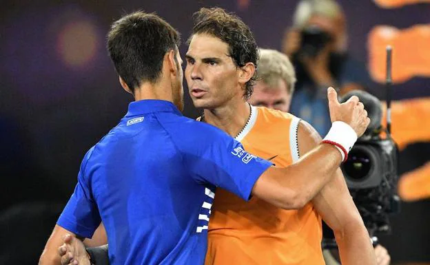 Djokovic y Nadal se abrazan al término de la final del Abierto de Australia. 