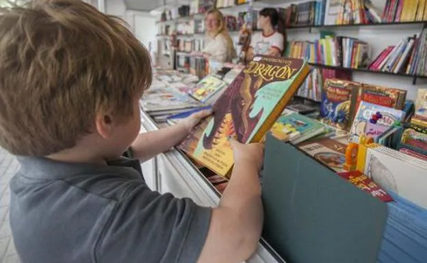 Un niño mira un libro en un puesto. 