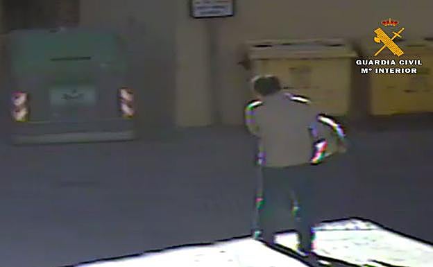 El detenido, con el animal a cuestas antes de arrojarlo al contenedor