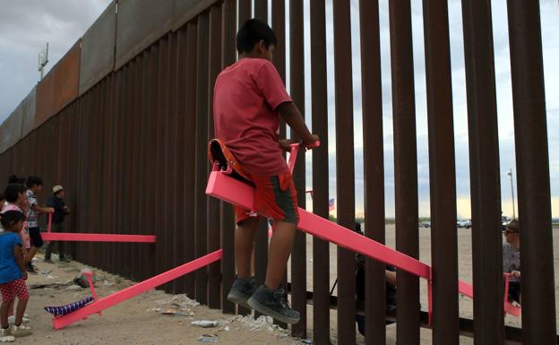 Un niño se columpia en el subibaja de la frontera. 