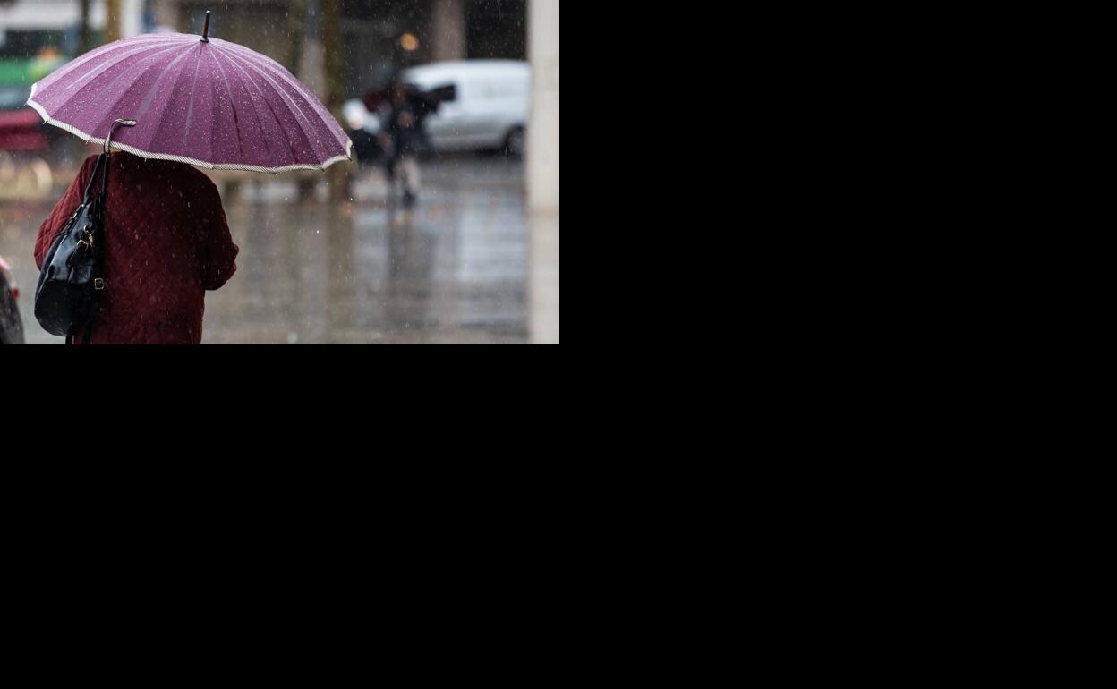 Una mujer se tapa con un paragüas.