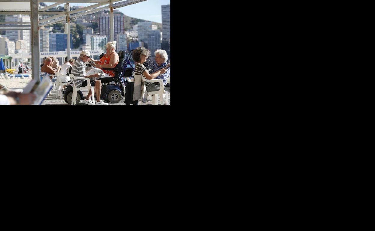 Varios turistas descansan este verano en un 'chiringuito' de Benidorm. 