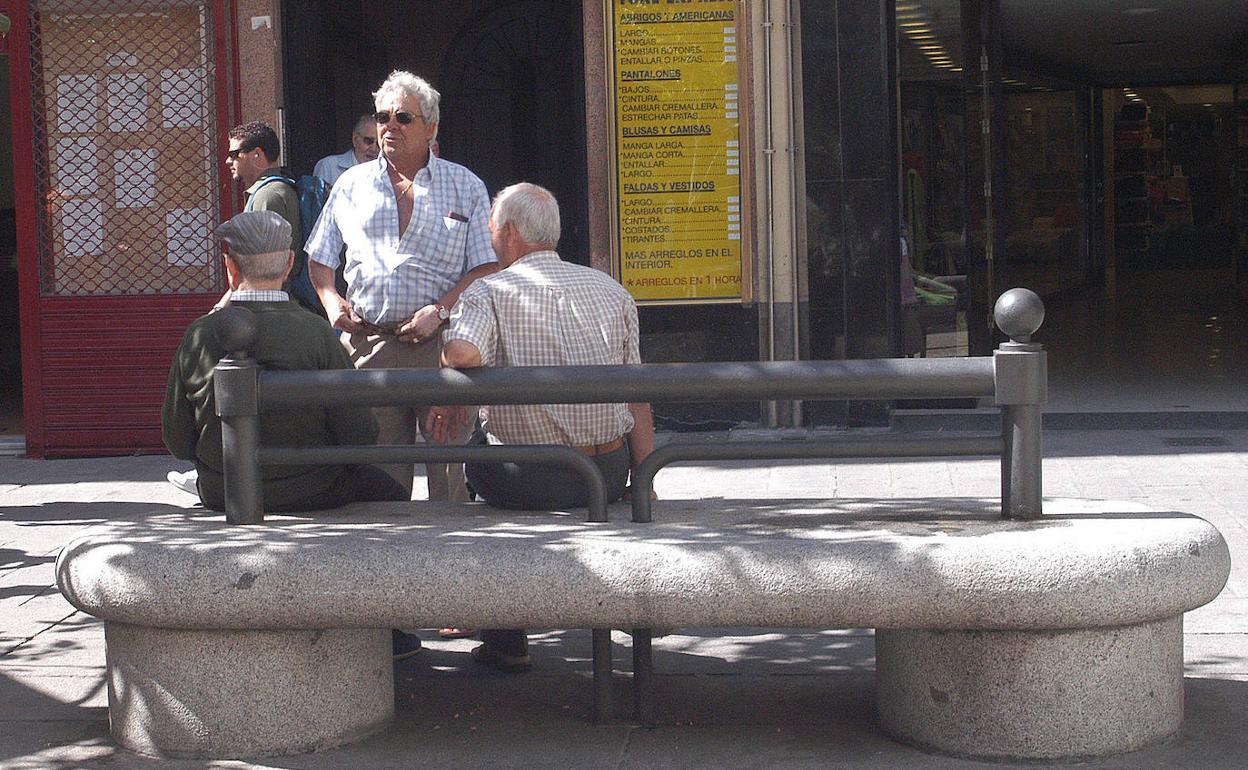 Un grupo de jubilados conversando en un banco.