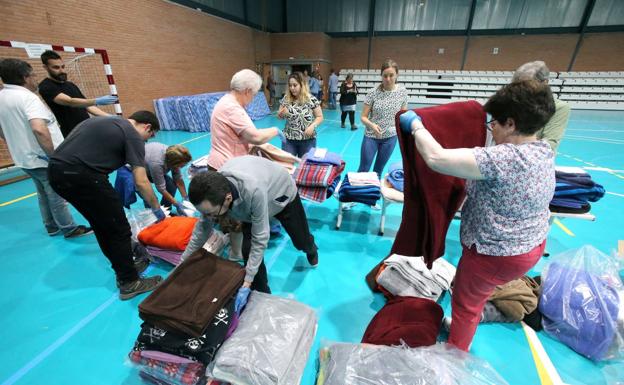 Voluntarios y trabajadores del centro de acogida preparan el polideportivo para los temporeros.