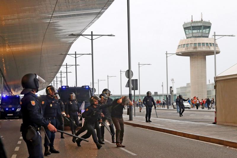 Miembros de los Mossos d'Esquadra cargan contra los centenares de personas que se agolpan ante el Aeropuerto del Prat 