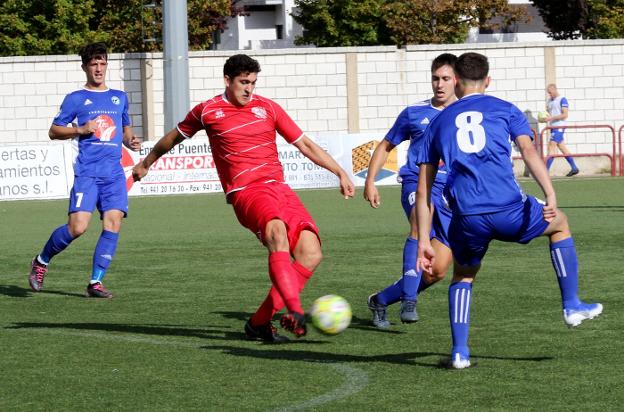 Navajas, que marcó para el Anguiano, juega el balón rodeado de futbolistas del Comillas.