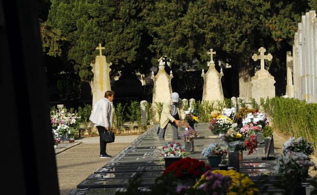Retoques en la decoración de un enterramiento, entre las distintas tumbas adornadas de flores