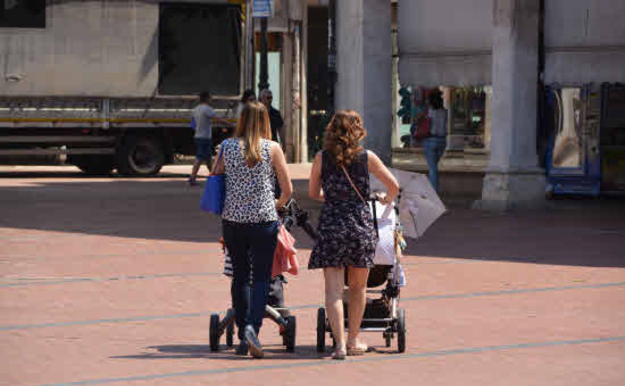 Dos madres pasean con sus hijos.