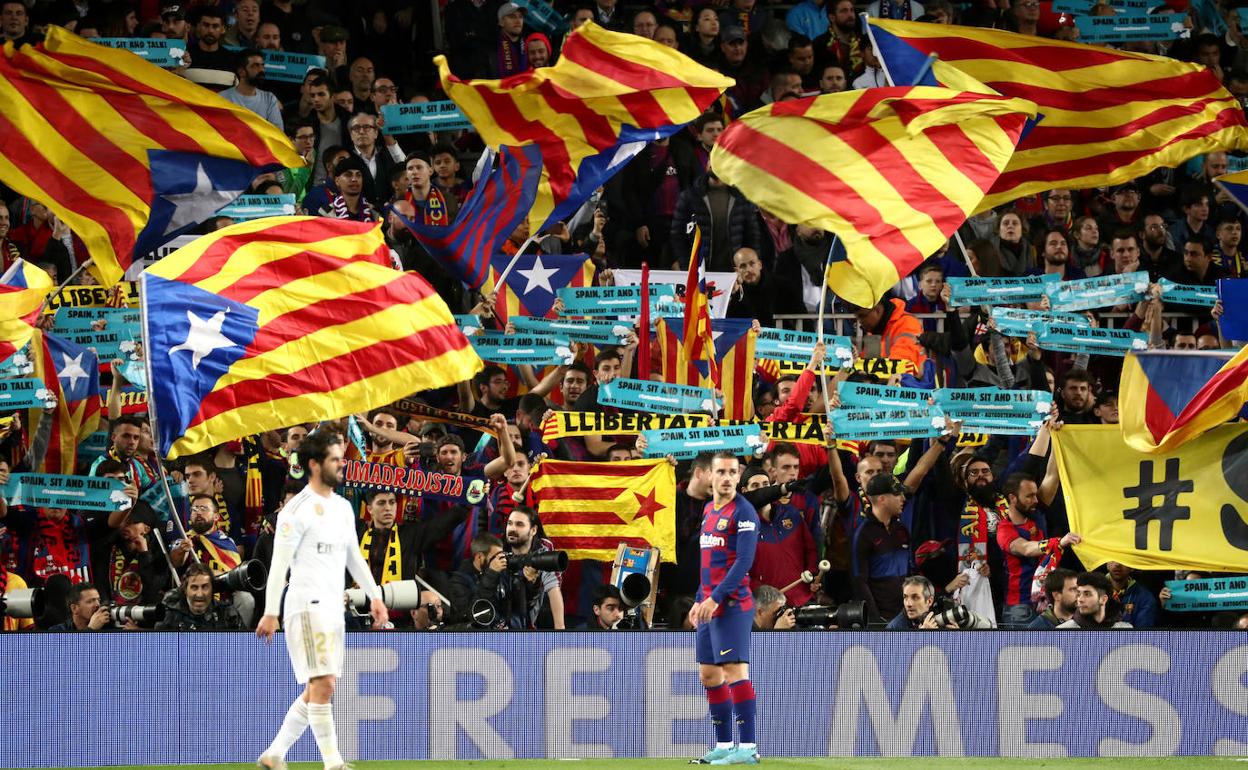 Los fanáticos agitan banderas esteladas y sostienen pancartas con lemas independentistas durante el partido de 'El Clásico' en el Camp Nou.