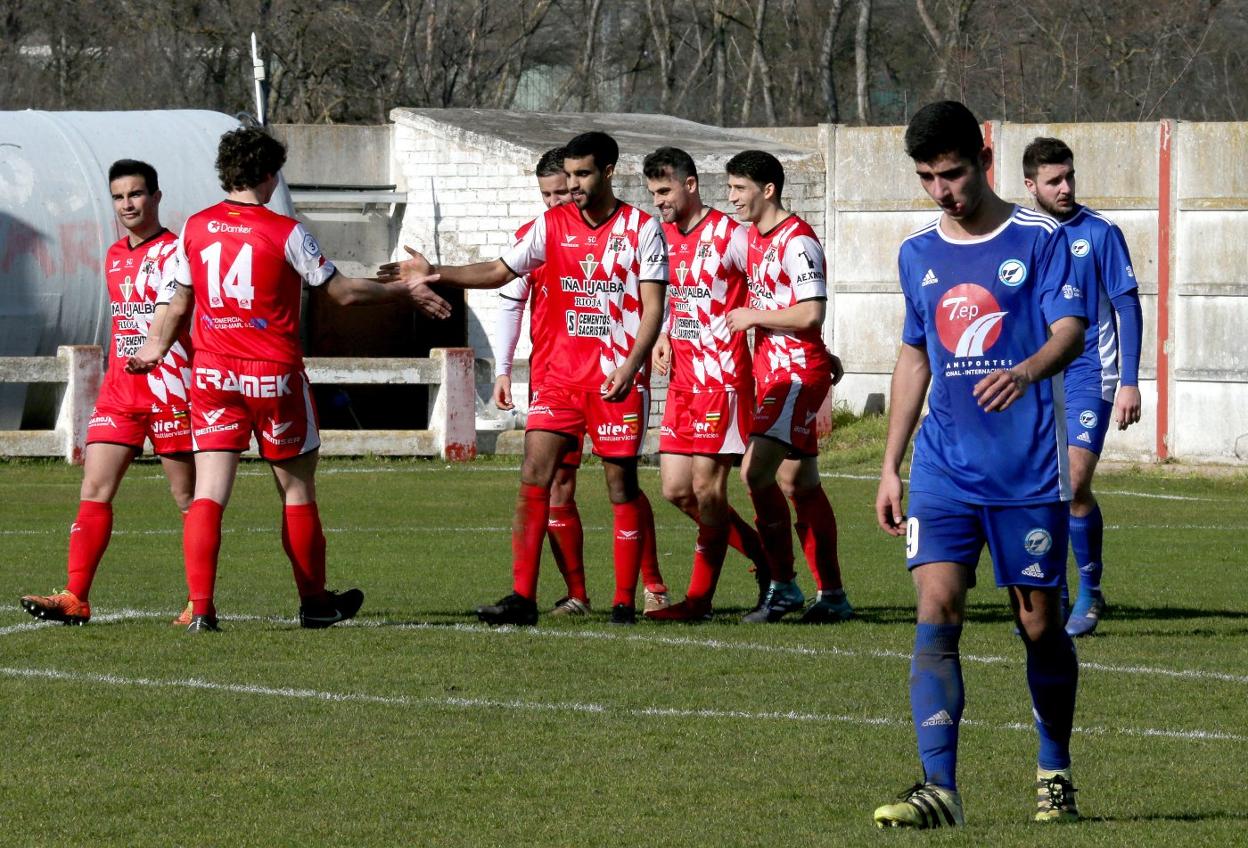 Aitor, que reapareció ayer tras una grave lesión, felicita a Ache por uno de sus tres goles ante la mirada perdida del Comillas.