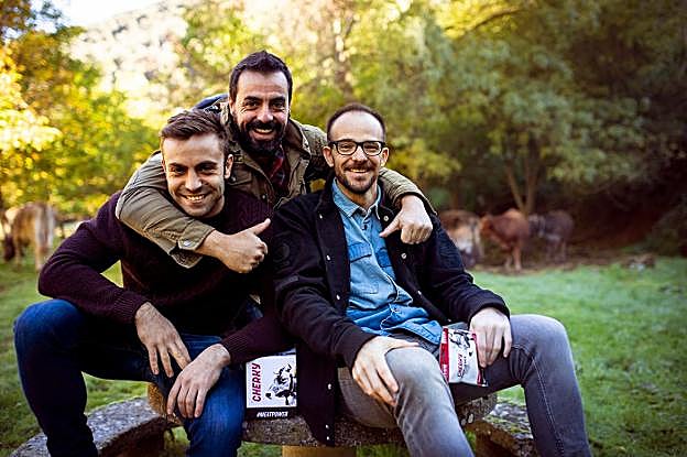 Carlos Camarero, David Saldaña y Javier Rioja posan con sus 'snacks' en un paraje con vacas. 