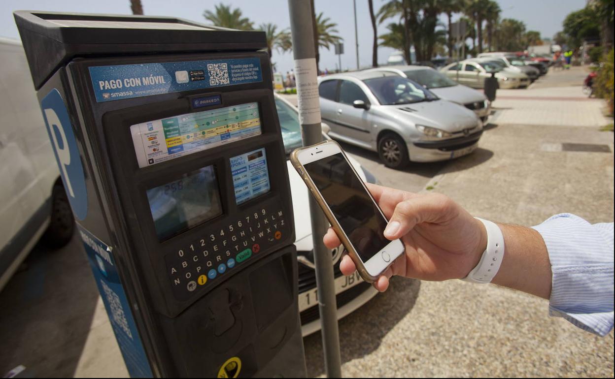 Un hombre paga su estacionamiento con el móvil.