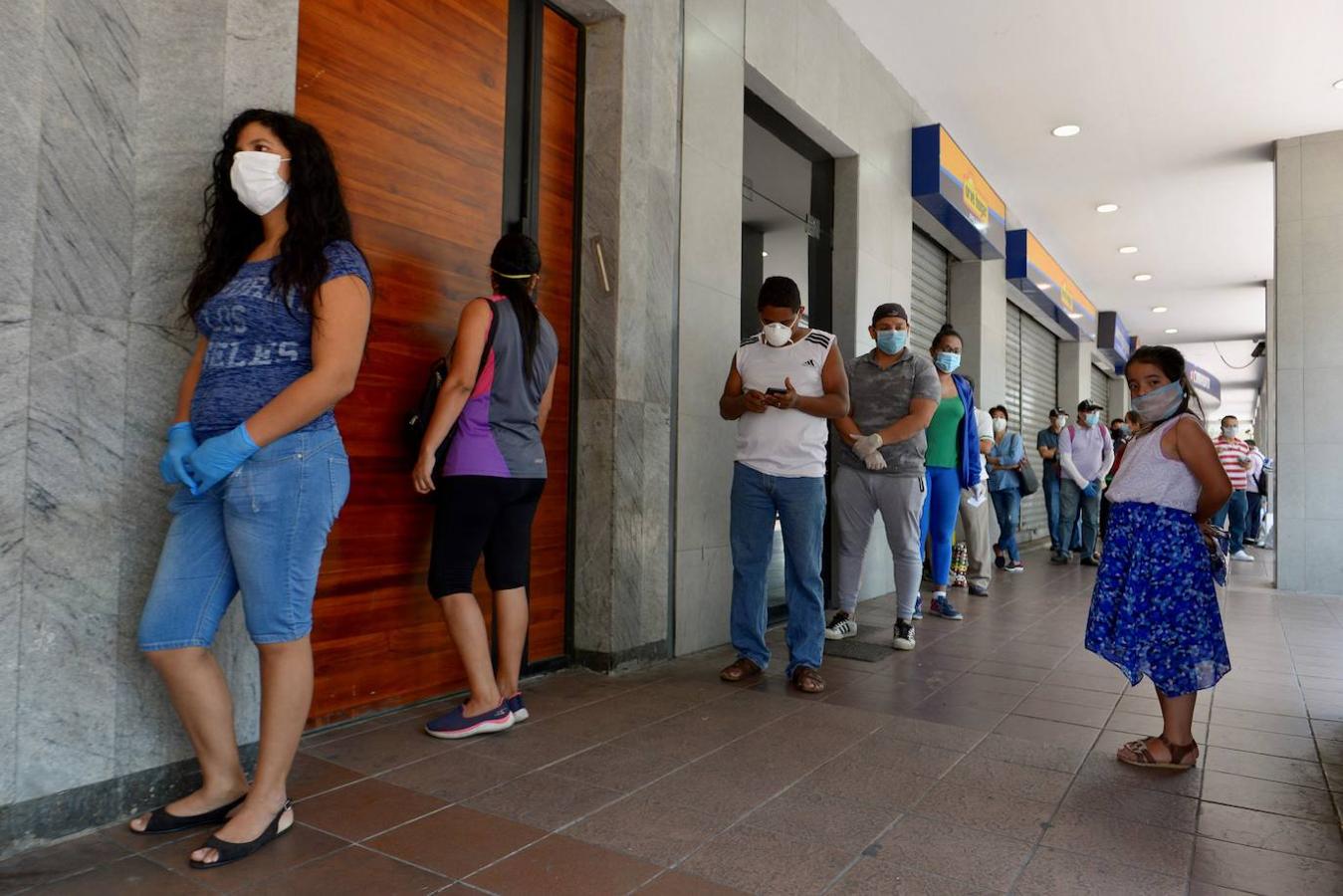 Ciudadanos con mascarillas hacen fila este martes para abastecerse de productos en un supermercado de Guayaquil (Ecuador).