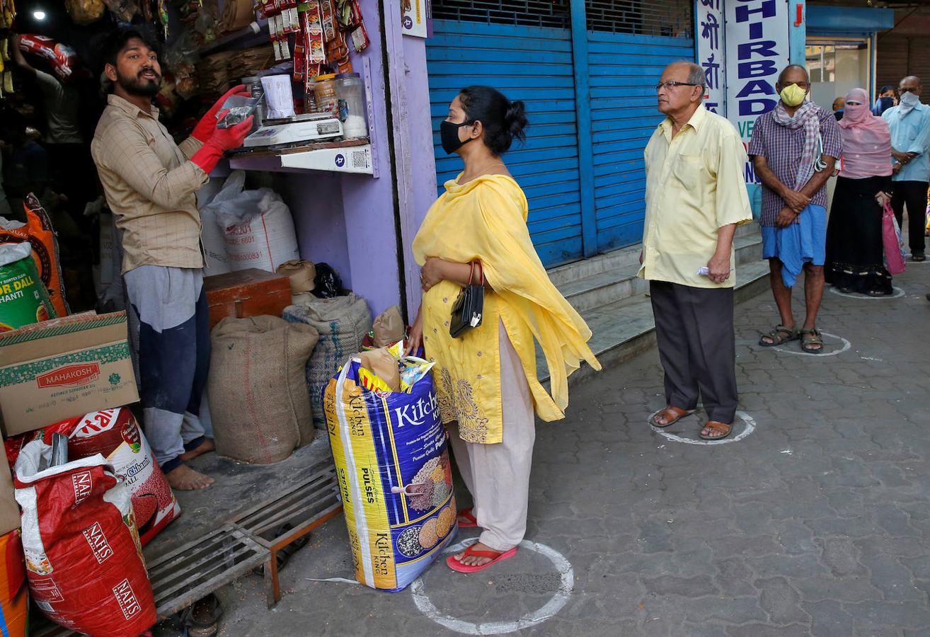 Un gran grupo de personas hacen fila en círculos dibujados para mantener una distancia segura mientras esperan comprar comestibles durante un cierre nacional, en Kolkata, India. 