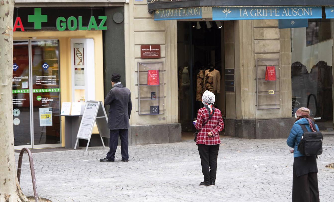 Un grupo de personas que hacen fila frente a una farmacia se mantienen a una distancia segura entre sí en medio de la pandemia de coronavirus COVID-19 en Lausana, Suiza.