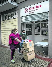 Imagen secundaria 2 - Arriba, María Ángeles Lacarra prepara alimentos mientras una mujer recoge fuera la caja que le han preparado. A la derecha, Pilar, con comida para bebés. A la izquierda, María Ángeles ayuda a Yorleny a empujar el carro. 