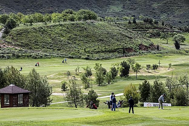 Cuatro golfistas inician su jornada por el hoyo 1 del campo de golf de Logroño. Al fondo, otros tres jugadores avanzan por el hoyo 11. 