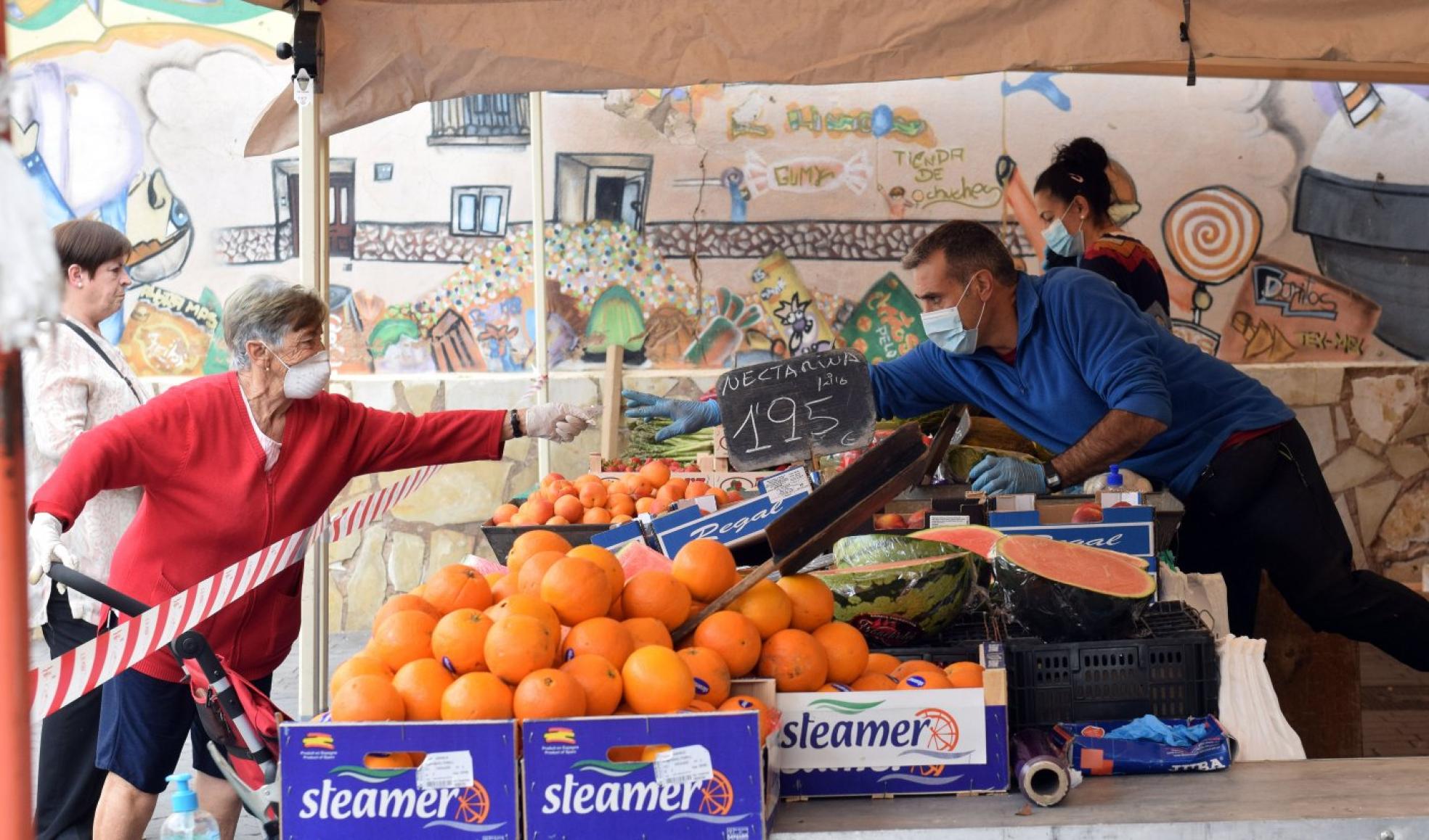 Una mujer paga su compra en el puesto de fruta y verdura de Murillo. 